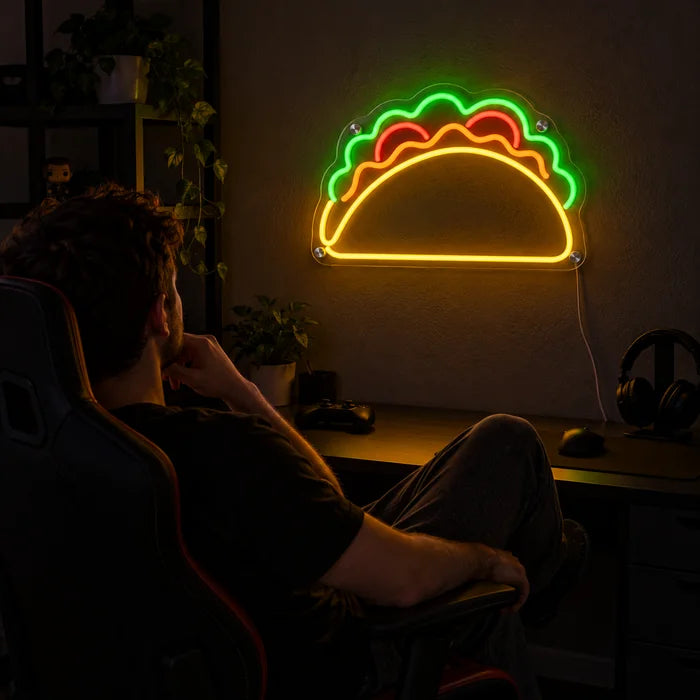 Taco-Zeit Neon LED Schild über dem Gaming-Schreibtisch, davor ein Spieler im Gaming-Stuhl