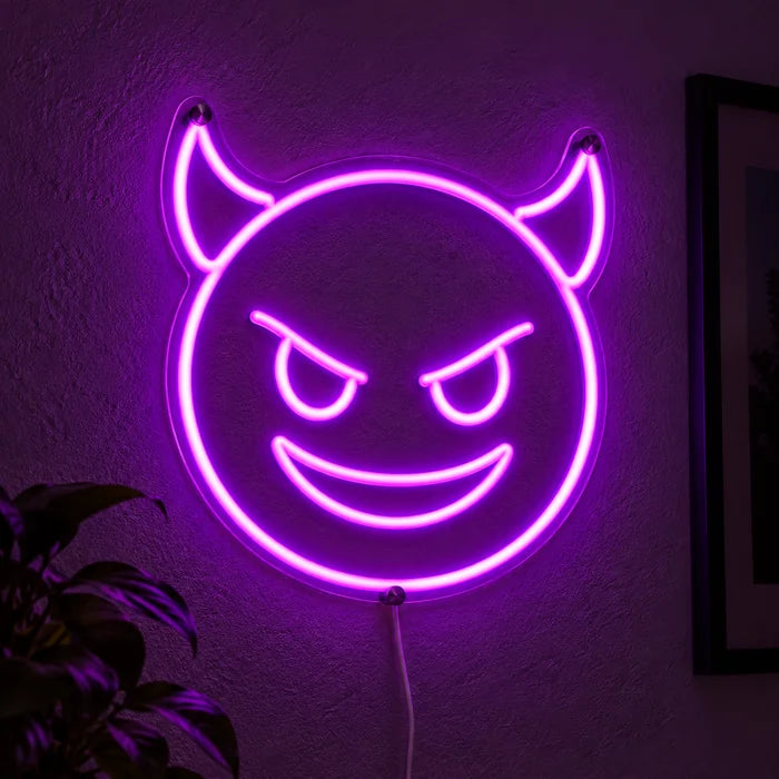 Teufelsgrinsen Neon LED Schild leuchtend an einer dunklen Wand, Nahaufnahme mit Anschlusskabel
