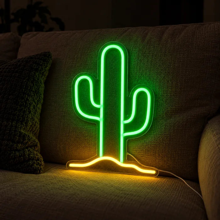 Wüstenkaktus Neon LED Schild auf einem gemütlichen Sofa zwischen Kissen und Decke