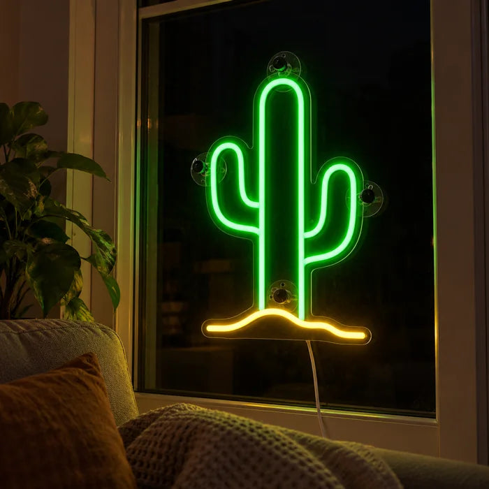 Wüstenkaktus Neon LED Schild abends im Fenster eines gemütlichen Wohnzimmers